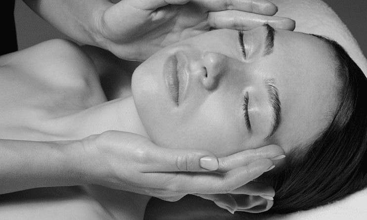 Woman receiving a gentle facial massage with closed eyes.