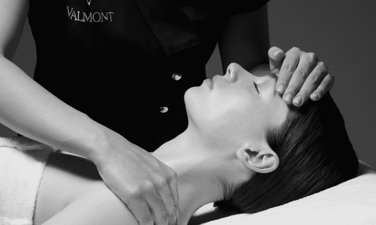 Person receiving a relaxing facial and neck massage in a spa setting.