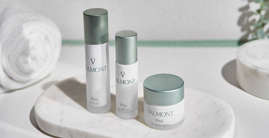 Valmont skincare products displayed on a marble tray in a bathroom setting.